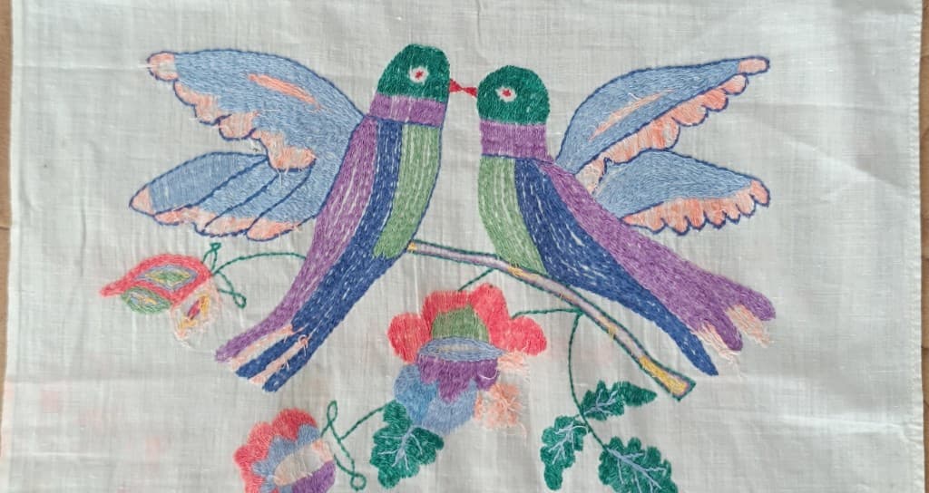 Deux oiseaux face à face sur une branche, broderie traditionnelle sur lin.