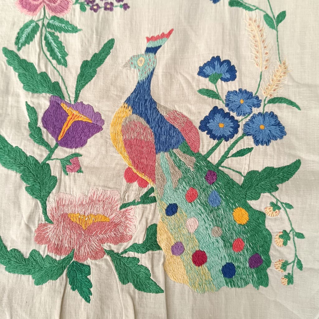 Motif paon et fleurs, broderie polychrome sur tissu naturel.