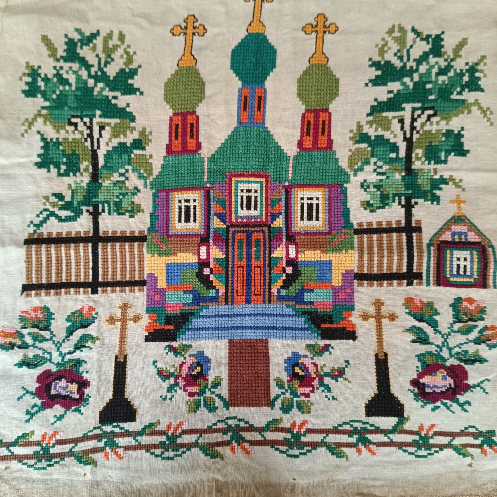 Broderie picturale : église à dômes verts, croix et arbres stylisés.
