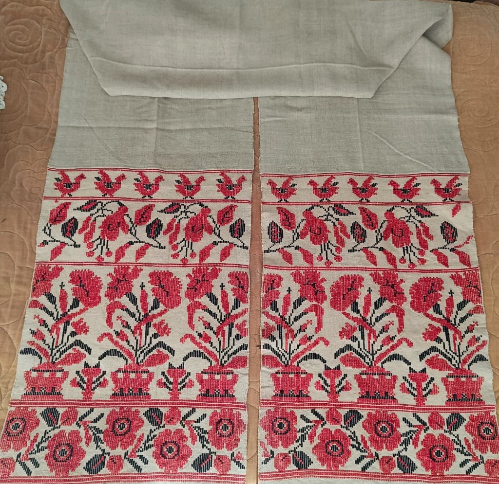 Rushnyk rouge et noir : oiseaux, fleurs en pot et frange, fond naturel.